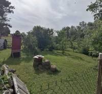 A garden with a lawn and trees, next to a family house in Hrkovce.