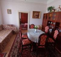 Living room in a family house with a sofa, dining table, and display cabinet.
