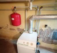 Boilers in the basement of a family house with installed piping and an expansion tank.