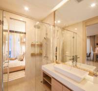 A bathroom in a 2-room apartment with a shower and a sink, leading to the bedroom.