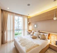 A bedroom in a 2-room apartment with modern furnishings and large windows letting in natural light.