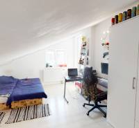 Attic room with a bed, desk, and wardrobe in a family house.