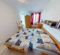 Bedroom in a family house with a bed, books, a cabinet, and a mirror.