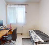 Interior of a family house with a bed, a desk, and a chair by the window.
