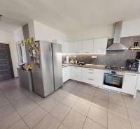 A kitchen in a family house with modern appliances, gray tiles, and white cabinets.