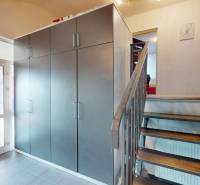 Entrance hall in a family house with a large wardrobe, staircase, and glass doors.