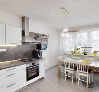 A kitchen in a family house with cabinets, a dining table, and a window with flowers.