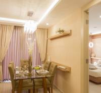 A softly lit dining room and living room with a set table in a 3-room apartment.