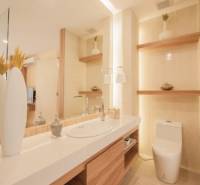 A bathroom in a 3-room apartment with a sink, toilet, and decorative shelves.