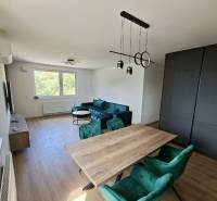 Dining room with a wooden table and green chairs in a 3-room apartment.