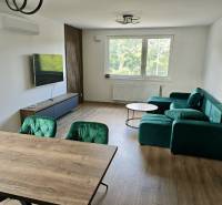 Living room in a 3-room apartment with a colorful sofa, dining table, and television.