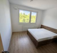 A bedroom in a 3-room apartment with a bed and a view of greenery.