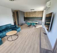 Living room and kitchen in a 3-room apartment with a turquoise sofa and a dining area.