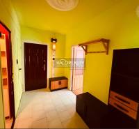 A hallway in a colorful 3-room apartment with a cabinet and a shelf.