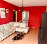 Living room in a 3-room apartment with a white couch, red walls, and a glass table.