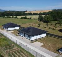 Family houses in Podlužany with modern roofs and solar panels in the field.