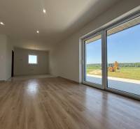 A spacious room with laminate flooring and large glass doors in a family house.