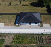 Family houses in Podlužany with solar panels, lawn, and garden.