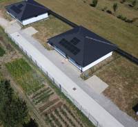 A family house in Podlužany with photovoltaic panels, a garden, and surrounding fields.