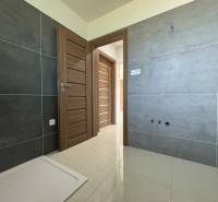 A bathroom in a family house with tiles, doors, and flooring in light shades.
