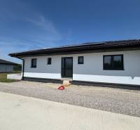 A family house in Podlužany with solar panels and a sloped roof on a gravel plot.