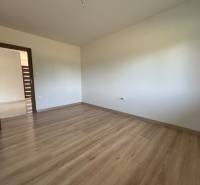 Empty room in a family house with wooden flooring and white walls.