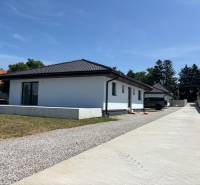 A family house in Podlužany with a white facade, a sloped roof, and a large driveway.