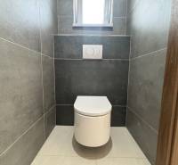 A toilet with tiles in a family house, minimalist design with gray tiles.