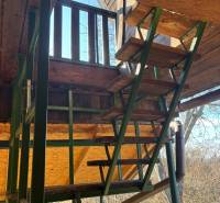 A wooden staircase to the recreational grounds, surrounded by nature, provides access to the elevated terrace.