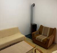 A room with a fireplace, recreational plots, a comfortable sofa, an armchair, and a coffee table.