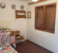 A kitchen with tiles, decorative plates, a wooden window, suitable for recreational purposes.