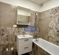 A bathroom with a bathtub, a sink, and tiles in a two-room apartment.