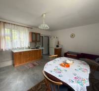 A kitchen in a family house with wooden furniture, a dining table, and a couch.