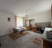 Dining room with a table and chairs, kitchen unit, and stove in a family house.
