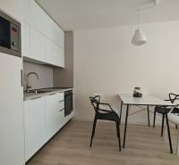 Kitchen corner in a studio apartment, white cabinets, table with chairs, wooden floor.