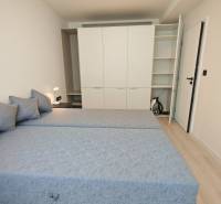 A bedroom in a one-room apartment with two beds, a built-in wardrobe, and a night lamp.