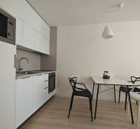 Kitchen corner in a studio apartment with white cabinets and a dining table.
