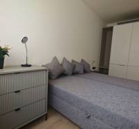 A bedroom with a double bed, wardrobe, dresser, and decorations in a studio apartment.