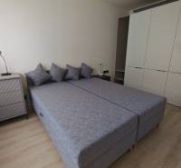 A bedroom in a one-room apartment with two beds, a chest of drawers, and a large wardrobe.
