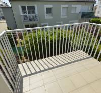 The balcony of a 2-room apartment in Rajka with a view of the garden and surrounding architecture.