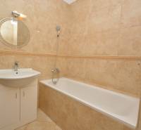 Bathroom amenities in a 2-room apartment with a shower and a sink with a round mirror.