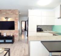 Living room with a kitchenette in a 2-room apartment, brick, TV, wooden floor.
