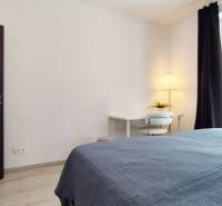 Bedroom in a 2-room apartment with a desk, lamp, and bed.