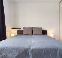 Bedroom in a 2-room apartment with a large bed, window with dark curtains.