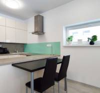 A kitchen in a 2-room apartment with a bar counter, stools, and decorative plants on the windowsill.
