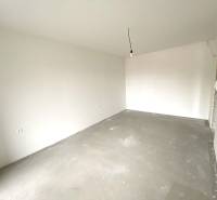 Empty room in a 2-room apartment with white walls and a concrete floor.