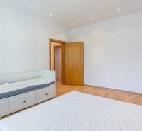 A room with a wooden floor, a bed, and white walls in a family house.