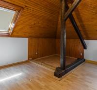 Attic room with wooden paneling, windows, and a radiator in a family house.