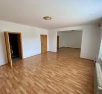 In the family house, there is a spacious room with a wooden floor and white walls.