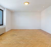 An empty room with parquet flooring and a large window in a family house.